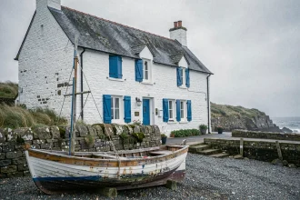 Maison de pêcheur bretonne aux murs en pierre blanchis et volets bleus sur le littoral atlantique