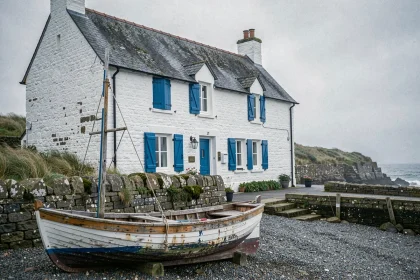 Maison de pêcheur bretonne aux murs en pierre blanchis et volets bleus sur le littoral atlantique